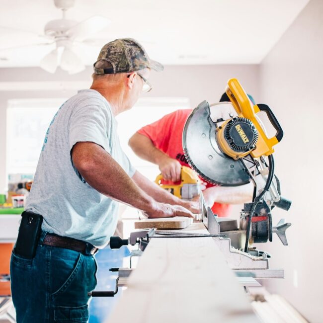 Vakman zaagt plank op maat Vakman zaagt nauwkeurig een houten plank op maat in een lichte werkruimte
