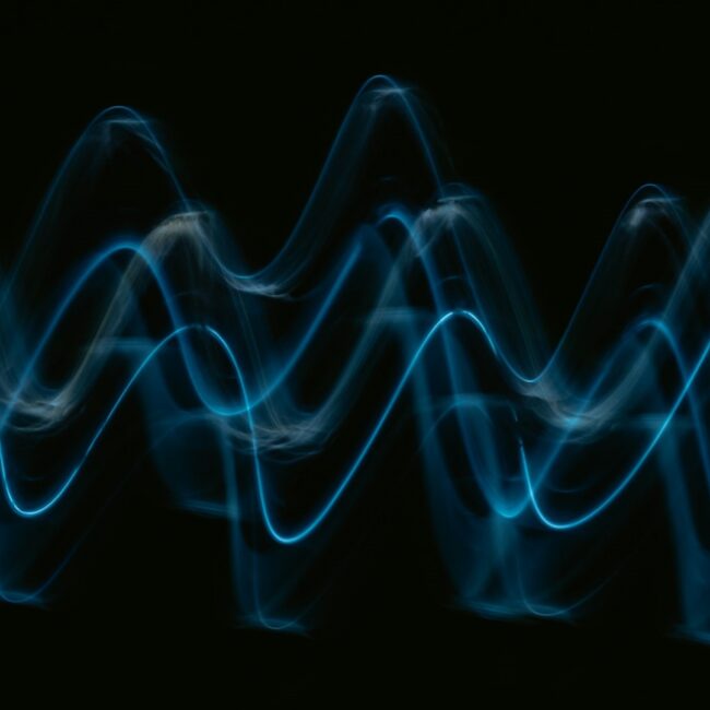 Visualisatie geluidsgolven Blauw lichtvisualisatie van geluidsgolven tegen zwarte achtergrond, passend bij het thema geluidsabsorptie.