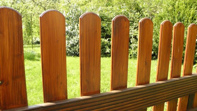 Houten schutting bij een groene tuin, passend bij een aanbouw met hout en erfafscheiding