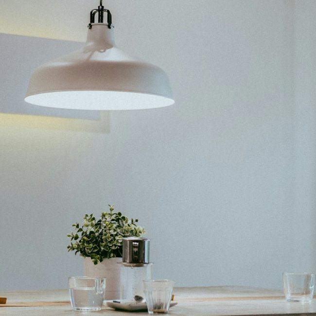 Donkere hoek verlichten met witte hanglamp en lichtreflectie op minimalistische tafel