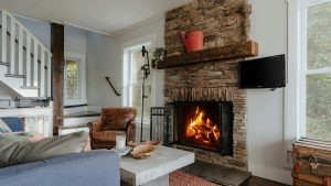 Landelijke woonkamer indeling met stenen haard, leren fauteuil en warme materialen voor extra comfort