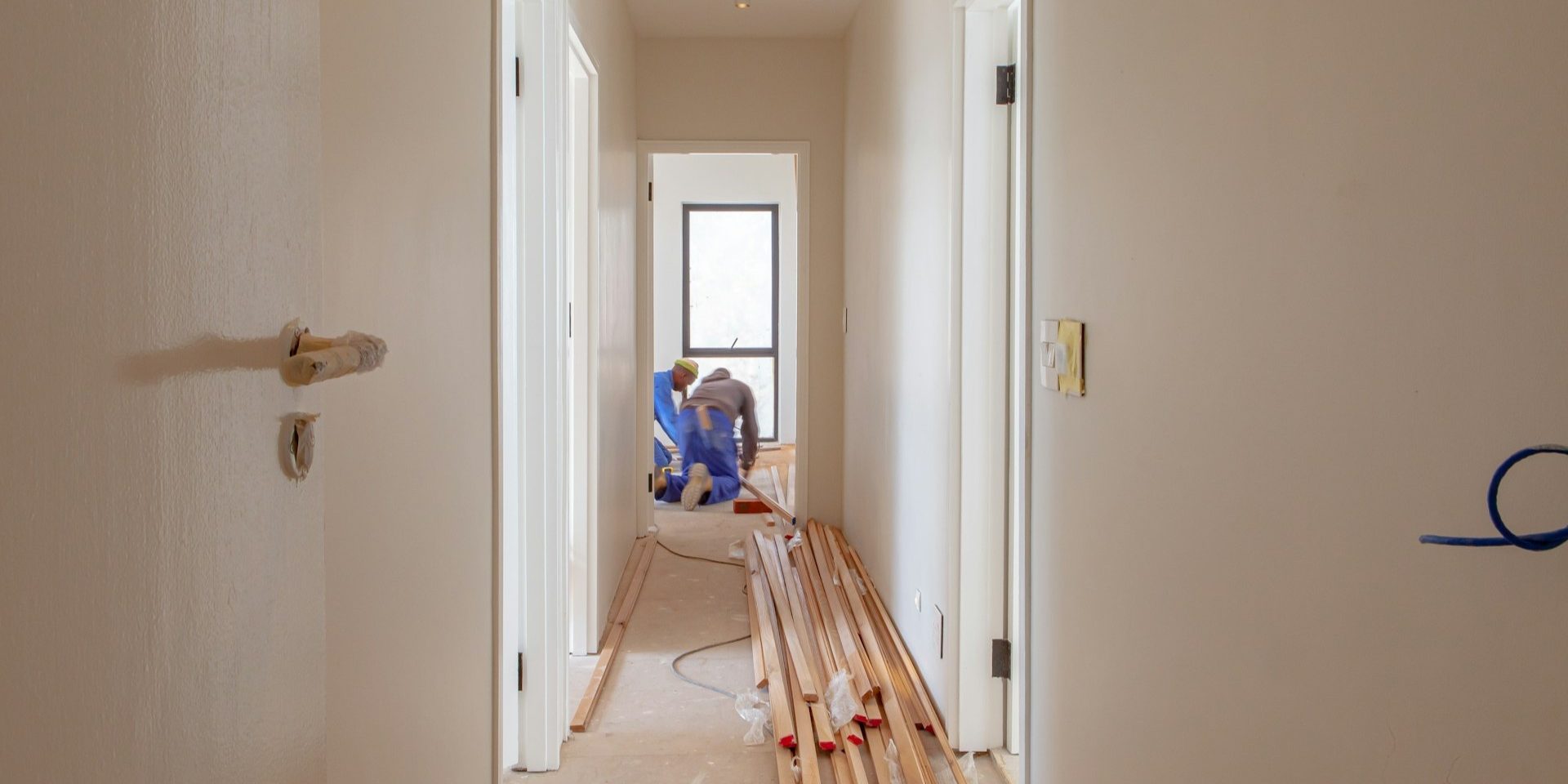 Renovatiebudget plannen tijdens woningrenovatie met nieuwe vloer en werkende vakmensen in smalle gang